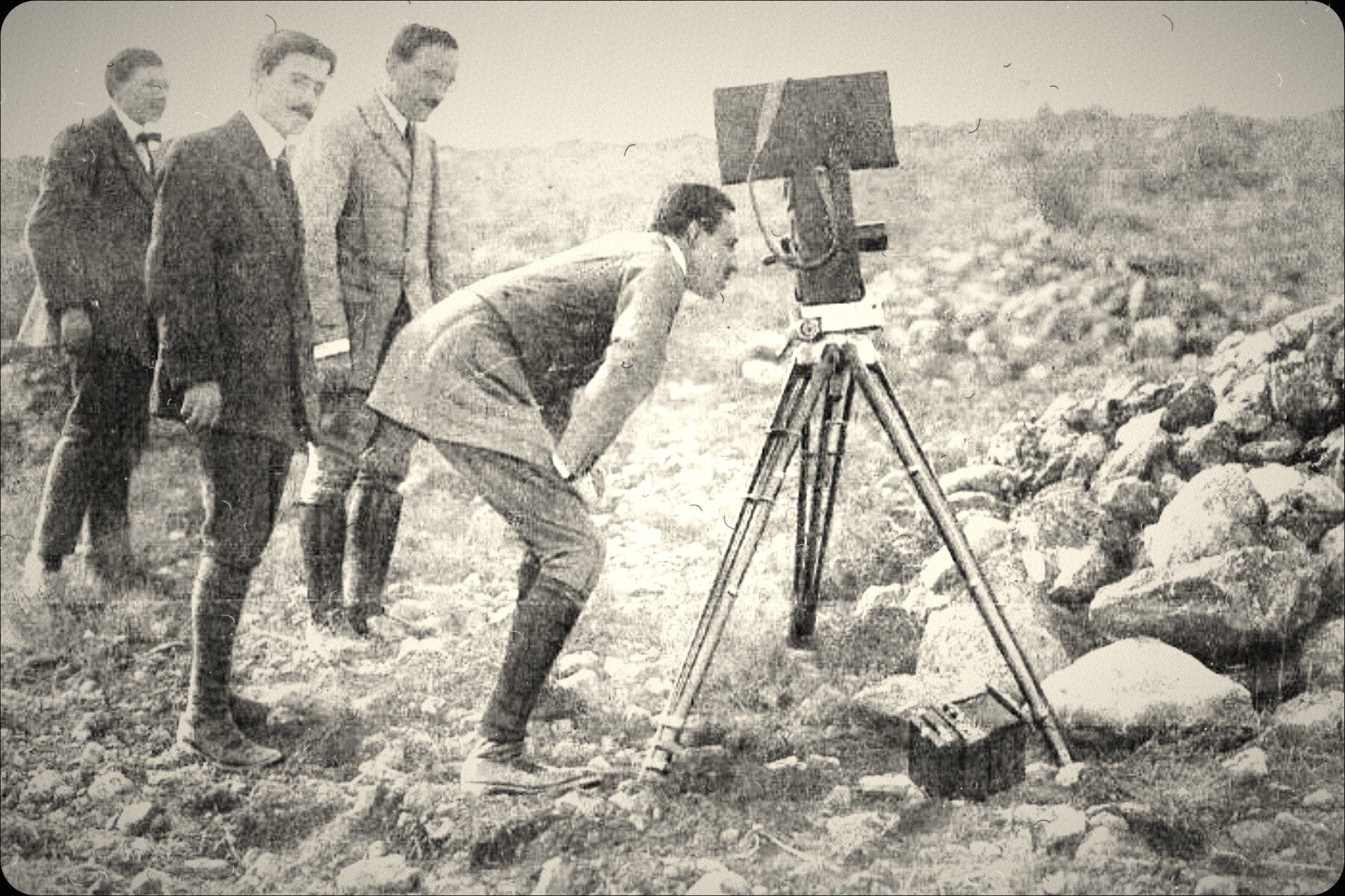 A film crew around a camera on a tripod in rocky country
